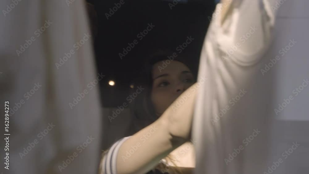 Couple Looks Through Clothes On Rack, Shot Through Store Window Couple Looks Through Clothes On Rack, Shot Through Store Window