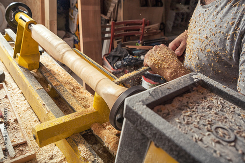 Fototapeta Naklejka Na Ścianę i Meble -  worker carpenter processes a wood  on a lathe