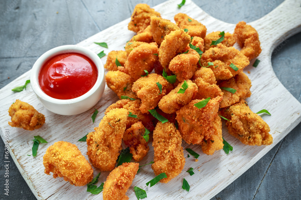 Fried crispy chicken nuggets with ketchup on white board Fried crispy chicken nuggets with ketchup on white board