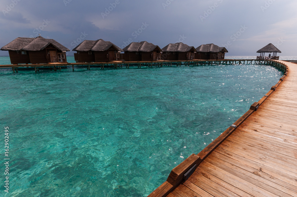 Tropical Maldives island resort with luxury water villas and wooden bridge
