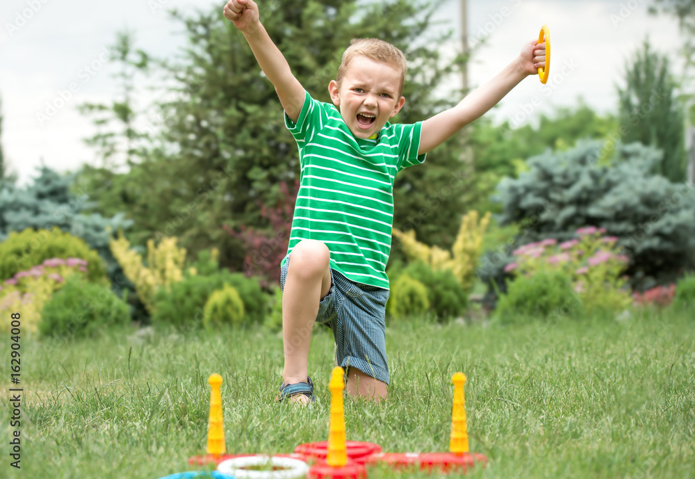 Cute boy playing a game throwing rings outdoors in summer Park. The joy