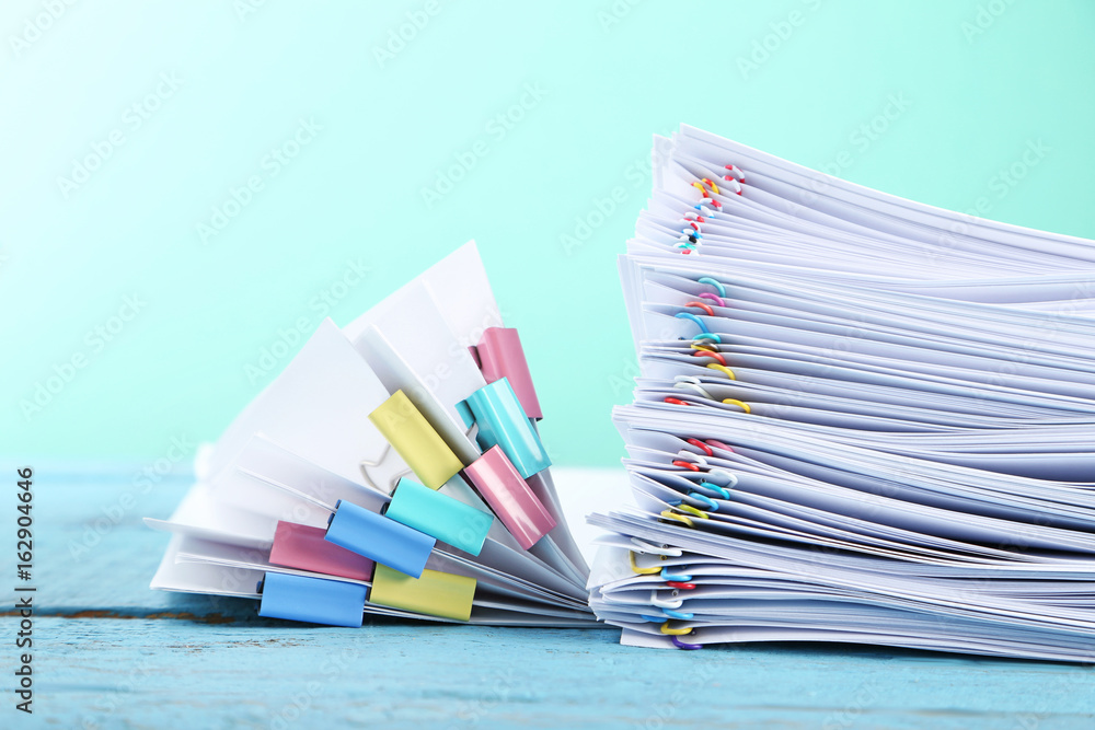 Stack of papers with paperclips and clamps on blue wooden table Stack of papers with paperclips and clamps on blue wooden table