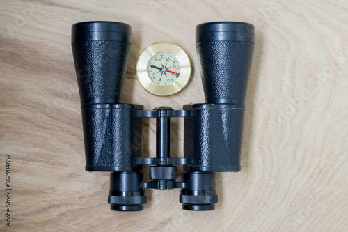 Binoculars and compass, traveler's things, on the wooden background photo