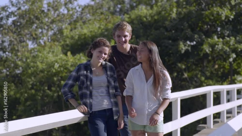 Multiethnic Teens Smile For Portrait On Bridge  photo