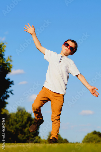 Portrait of funny boy dancing in summer park