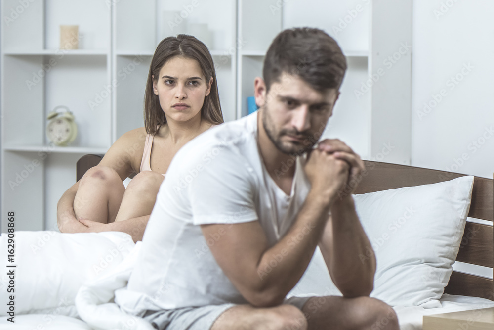 The depressed man sit near the woman in the bed