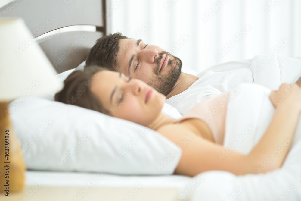 The man and woman sleeping in the comfortable bed The man and woman sleeping in the comfortable bed