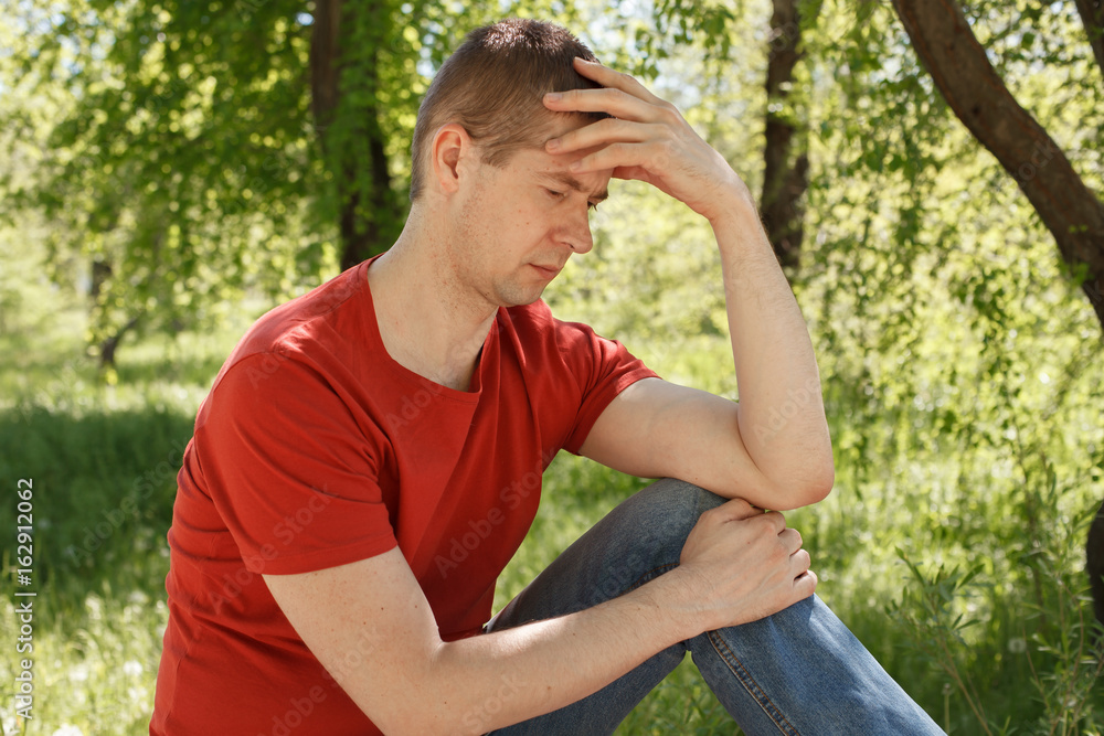 The man in a red t-shirt and jeans in the park The man in a red t-shirt and jeans in the park