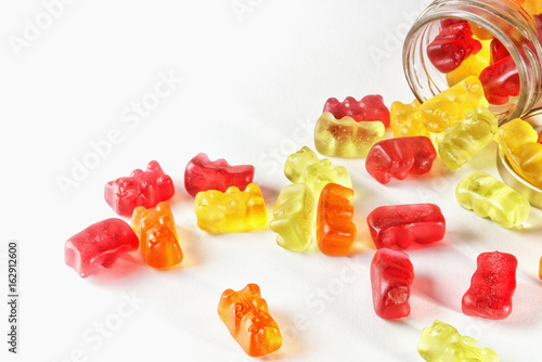 Gummies on isolated background poured from glass jars
