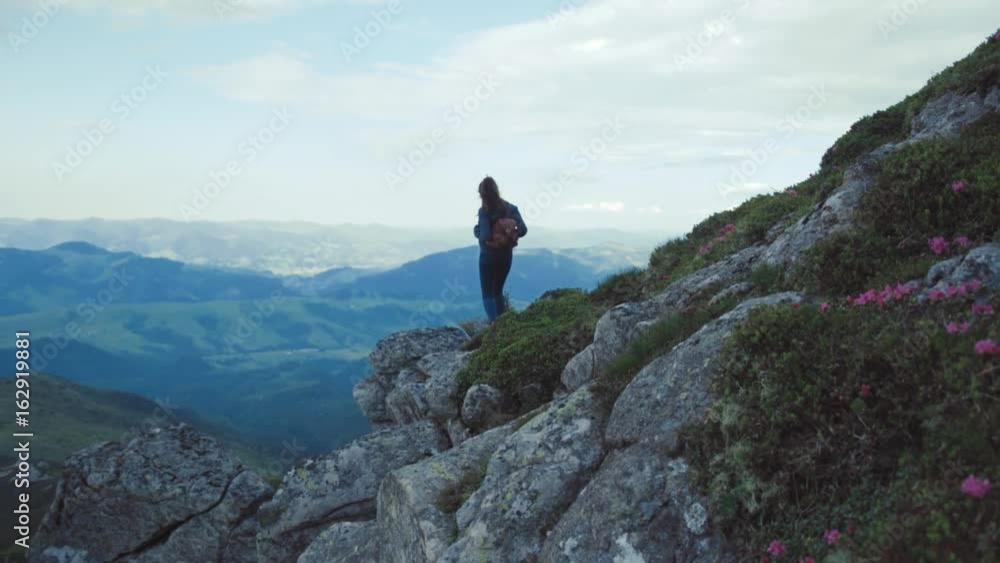 Beautiful young woman with a backpack stands alone on the mountain high, enjoying the view. Beautiful nature, gorgeous scenery. Being happy, feeling freedom. Mountain cliffs around. Beautiful young woman with a backpack stands alone on the mountain high, enjoying the view. Beautiful nature, gorgeous scenery. Being happy, feeling freedom. Mountain cliffs around.