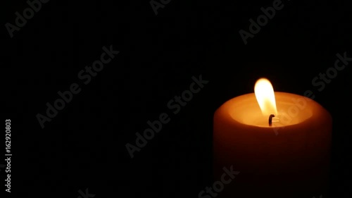 Closeup of burning candle isolated on black background
