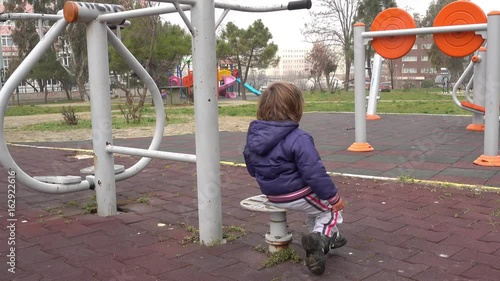 4K Handsome blowzy kid spinning around on playground