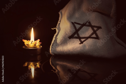 A burning candle next to the star of David photo
