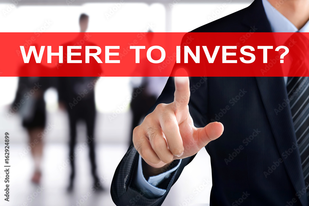 Businessman hand touching WHERE TO INVEST? tab on virtual screen Businessman hand touching WHERE TO INVEST? tab on virtual screen
