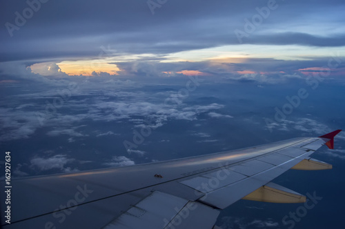 Through the windows of an airplane overlooking sunset on high altitude.