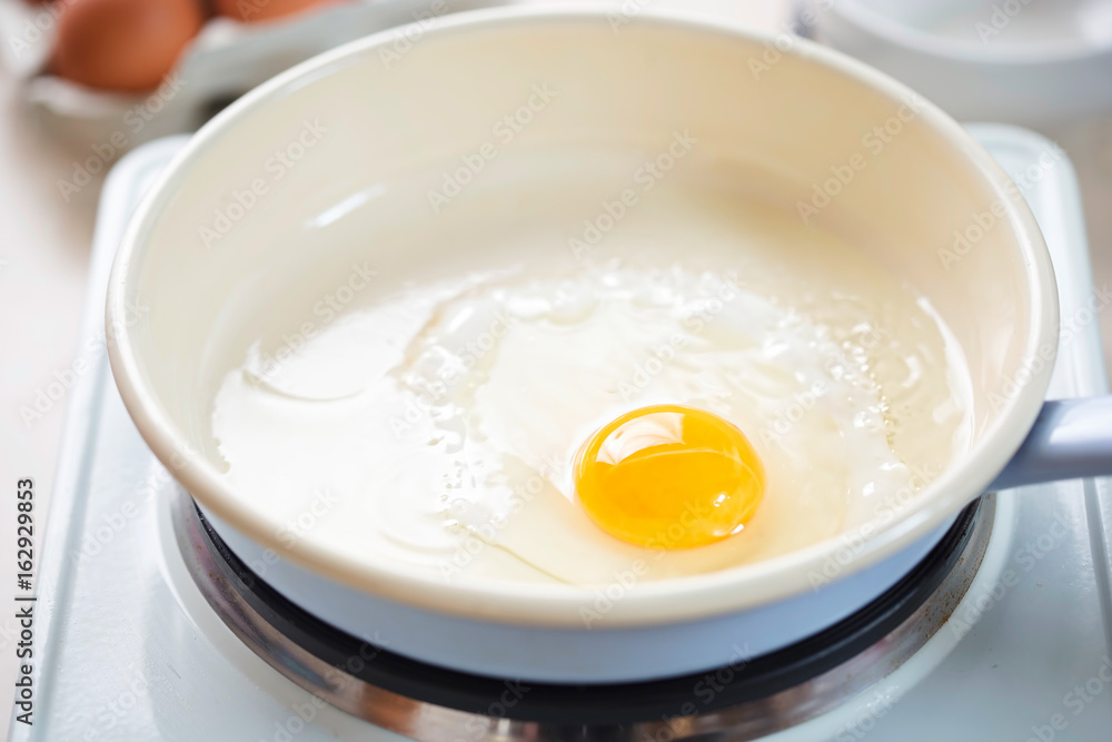 Egg fried on vegetable oil on blue pan 