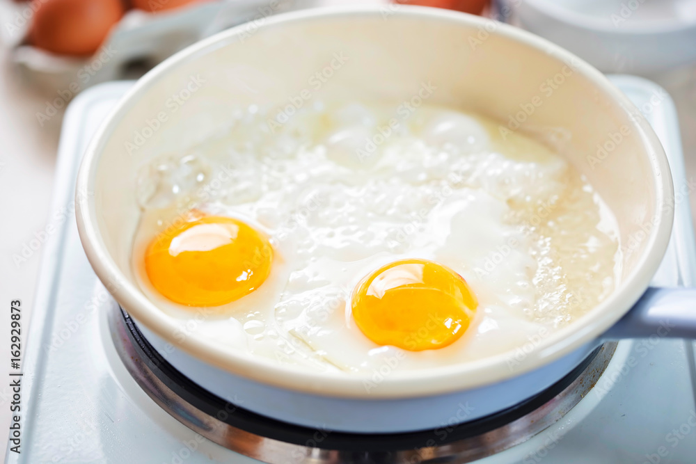 Egg fried on vegetable oil on blue pan Egg fried on vegetable oil on blue pan