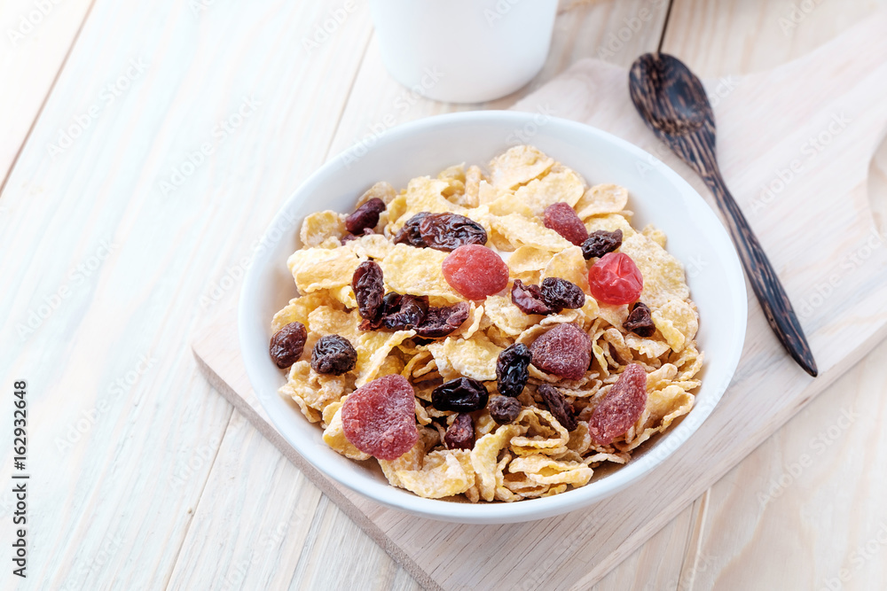 cornflakes and dry berry fruits in a white bowl on a wooden background. cornflakes and dry berry fruits in a white bowl on a wooden background.