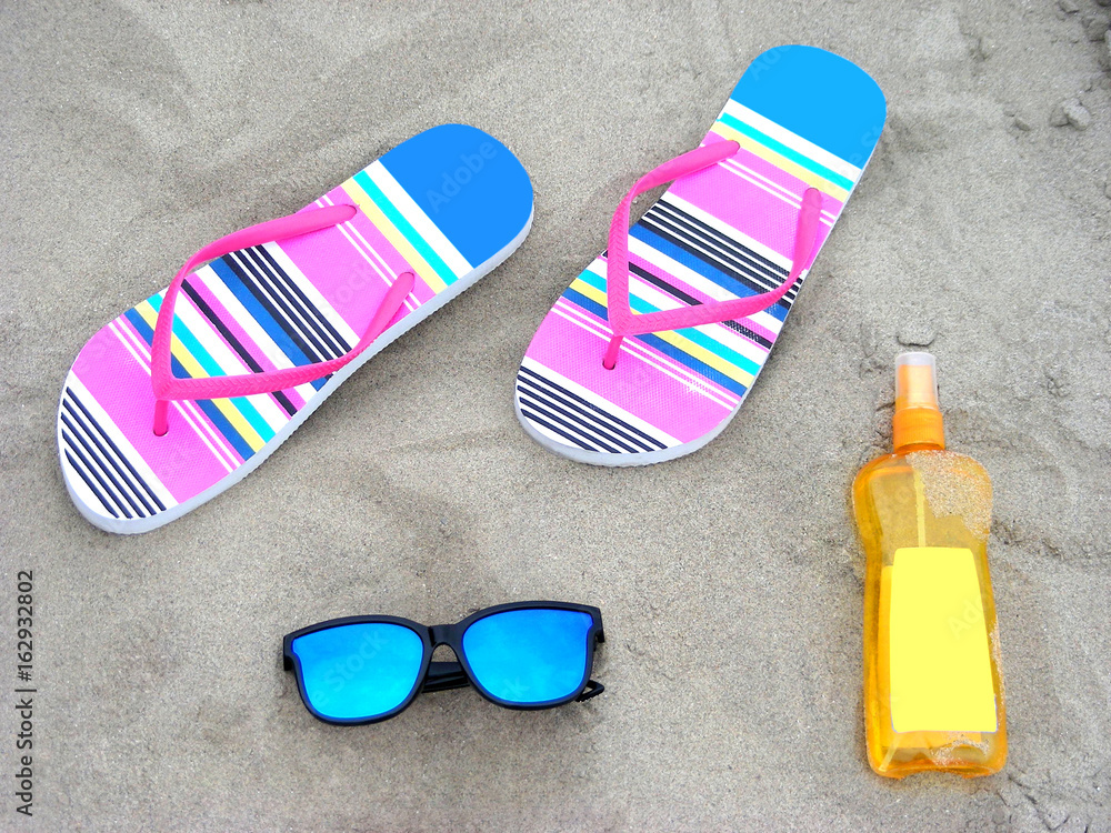 Naklejka premium Colorful flip-flops, sunglassess and sun-care milk