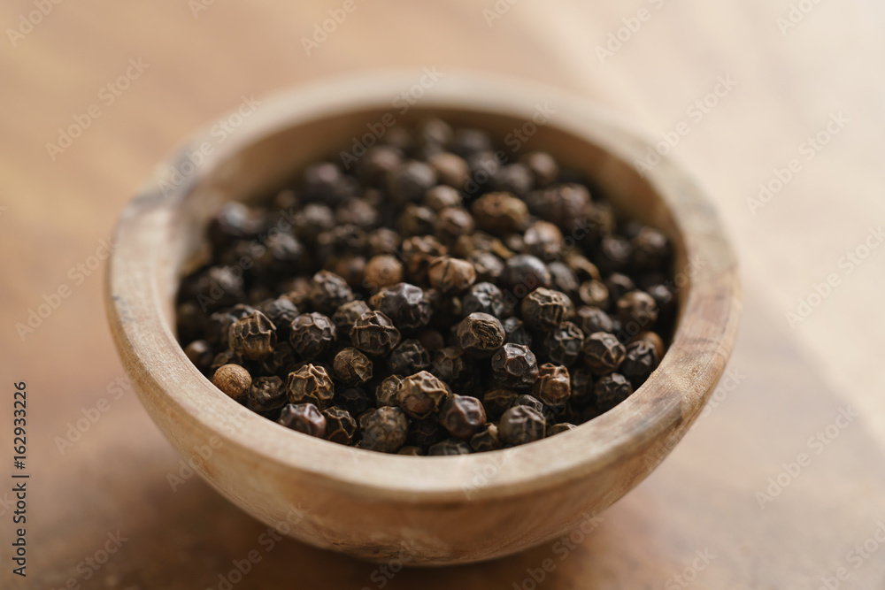 black dry pepper in wooden bowl on table black dry pepper in wooden bowl on table