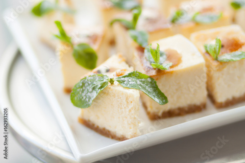 Appetizing cheesecake with mint leaves. Delicious sliced dessert on white plate.