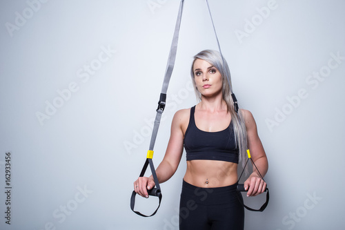 Sexy female fitness model training on a home training device in a studio
