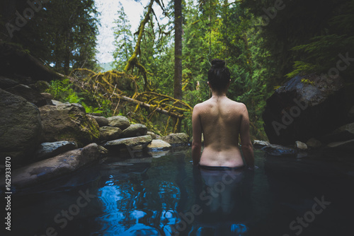 Young caucasian woman standing in natural hot spring bare back