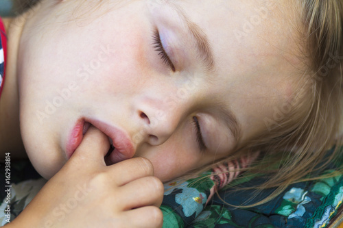 Φωτογραφία Little pretty girl sleeping, sucking thumb and having sweet dreams