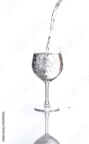 pouring water into a glass wine on white background