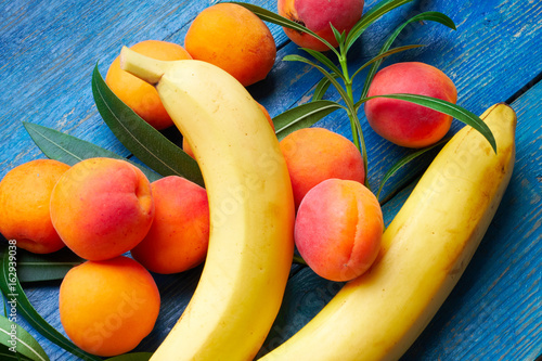 Fotografie Fresh apricots and bananas on blue background