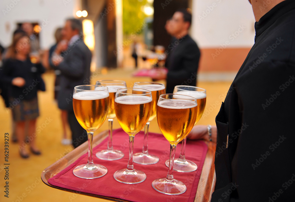 Obraz premium Waiter with cold beer glasses on tray
