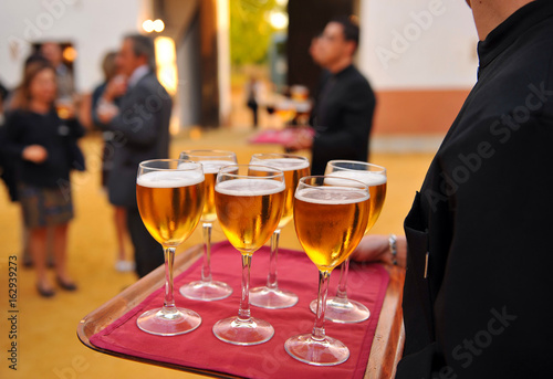 Waiter with cold beer glasses on tray