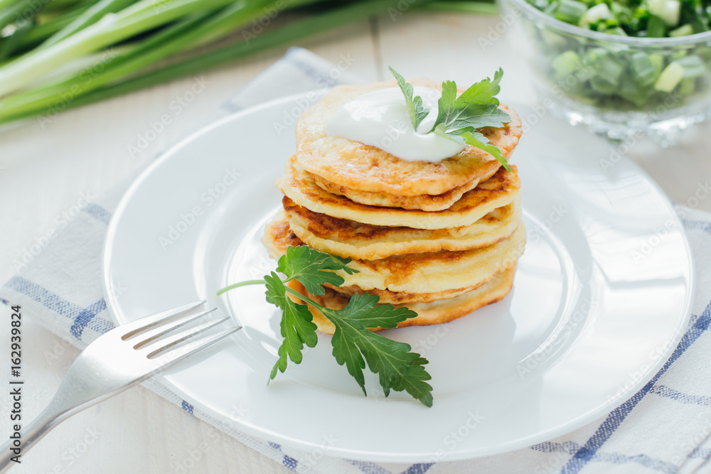 Stack of fried vegetable fritters with sour cream on top Stack of fried vegetable fritters with sour cream on top