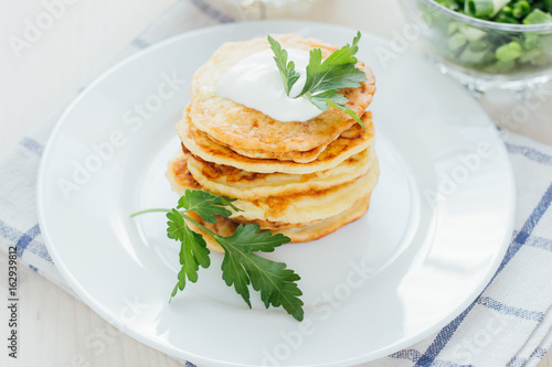 Stack of fried vegetable fritters with sour cream on top 