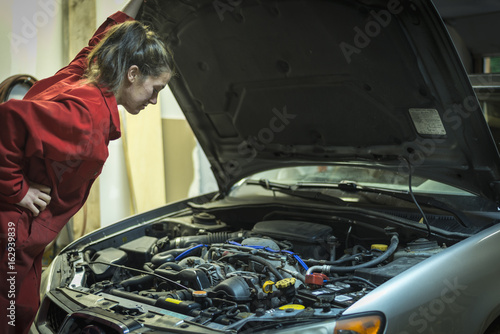Female mechanic inspecting car engine