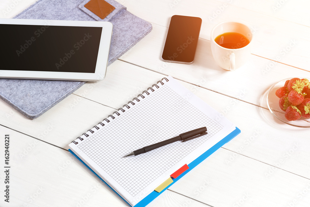 Office table desk with set of supplies, white blank notepad, cup, pen, tablet on white background. Top view Office table desk with set of supplies, white blank notepad, cup, pen, tablet on white background. Top view