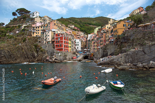 A charming summer-rich, colorful summer landscape with boats on the coast of Riomaggiore in Cinque Terre, Liguria, Italy, Europe