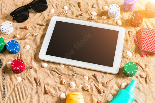 Gambling on vacation concept - white sand with seashells , colored poker chips and cards. Top view