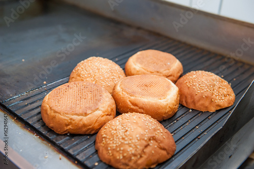 Burger restaurant menu cooking process. Buns are fried on a grill. Fast food cafe cuisine. Selective focus. close up photo