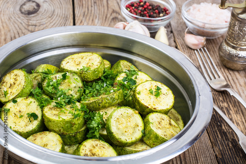 Warm salad with young zucchini with herbs and garlic in metal bo