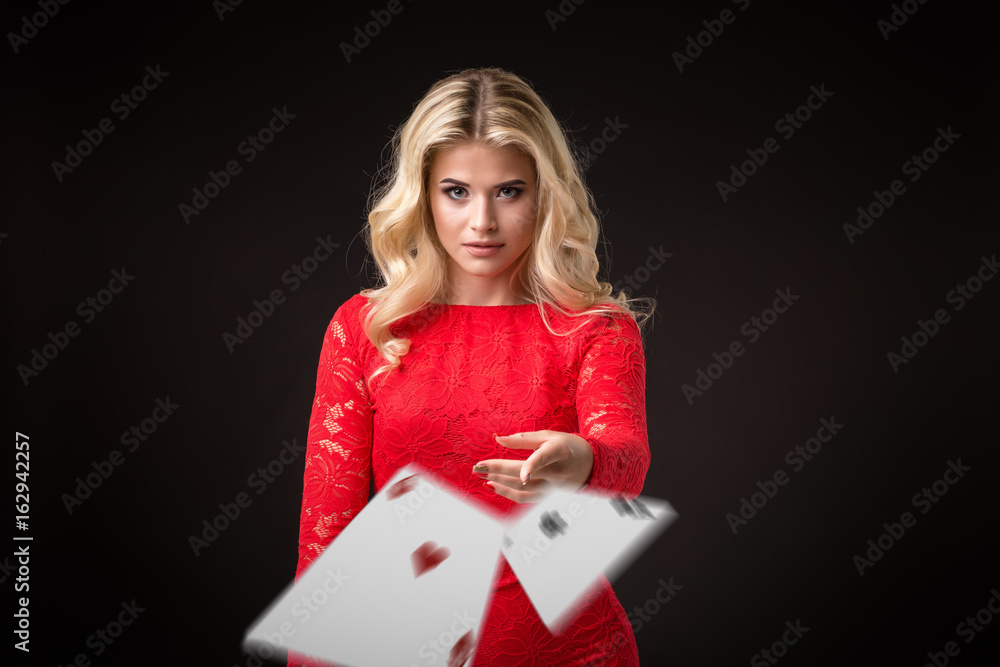 Young beautiful emotional woman throws cards on a black background in the studio. Poker Young beautiful emotional woman throws cards on a black background in the studio. Poker