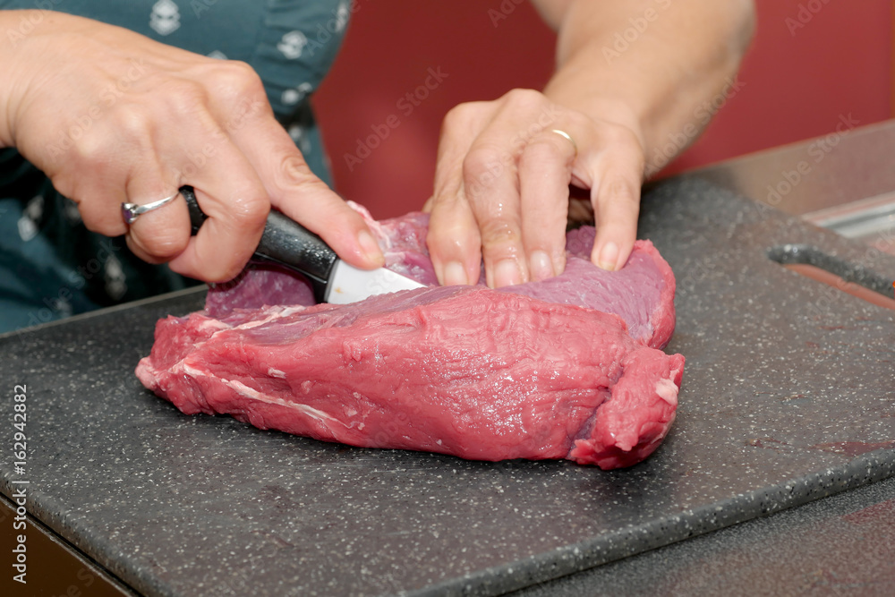 Woman's hands cutting meat