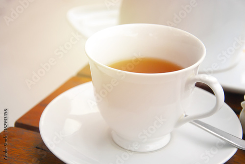 close up white cup of Tea on the wooden table with flare lens