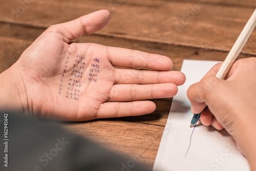 People cheating on test by writing answer on hand