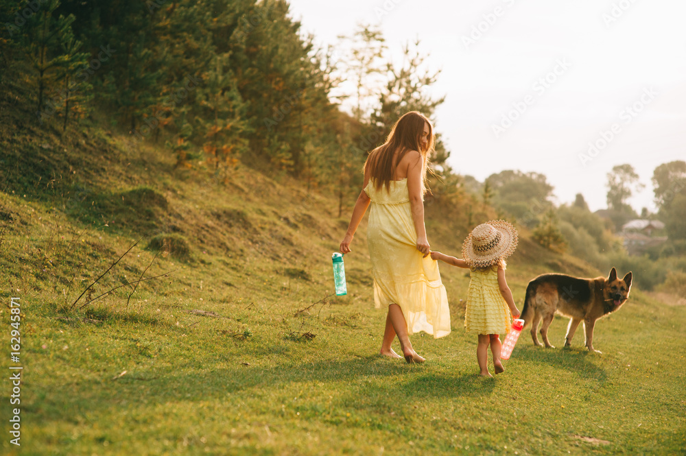 mother walk with his little daughter, and their dog mother walk with his little daughter, and their dog
