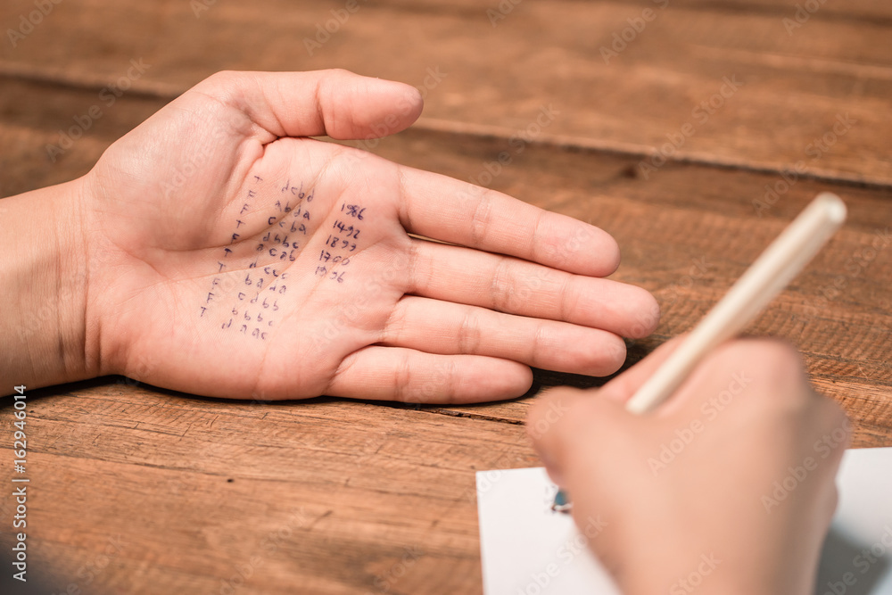 People cheating on test by writing answer on hand