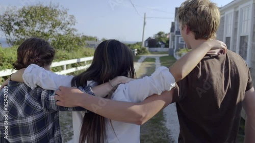 Multiethnic Teens Walk Down Road Together On Beautiful New England Seaside Road photo