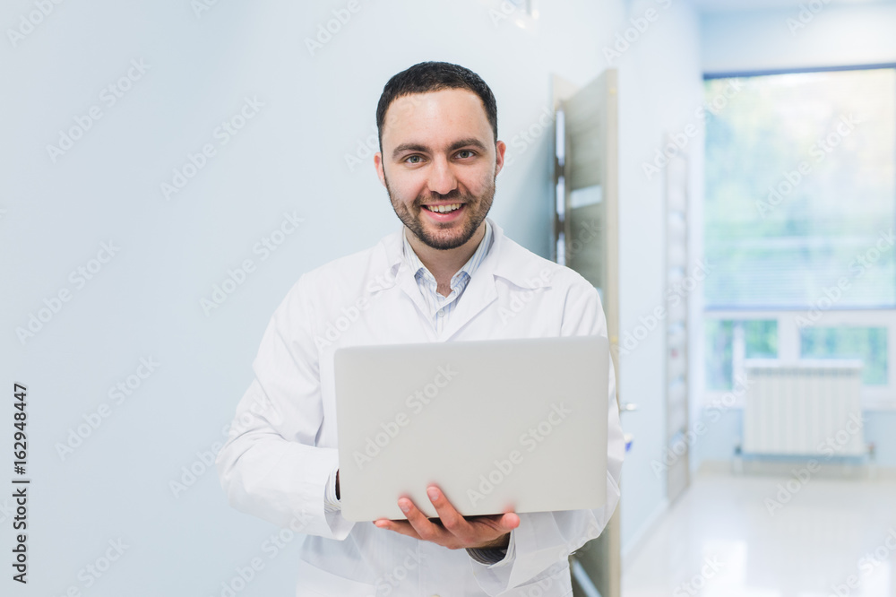 Portrait of cheerful doctor sitting at the desk working on laptop Portrait of cheerful doctor sitting at the desk working on laptop