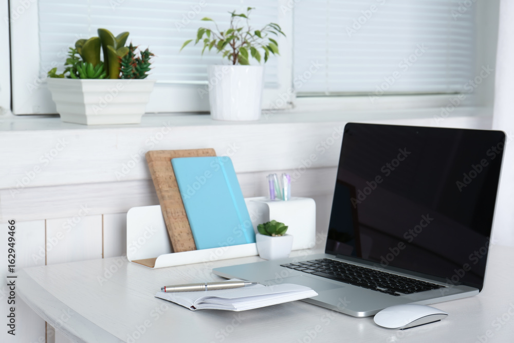 Comfortable workplace with modern laptop and blinds on window Comfortable workplace with modern laptop and blinds on window