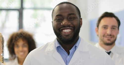 African American Scientist Man Happy Smiling Over Mix Race Team Of Researchers In Modern Laboratory Slow Motion 60